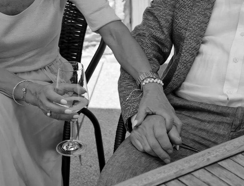 Close-up of a couple sharing an intimate moment, holding hands with a wine glass.